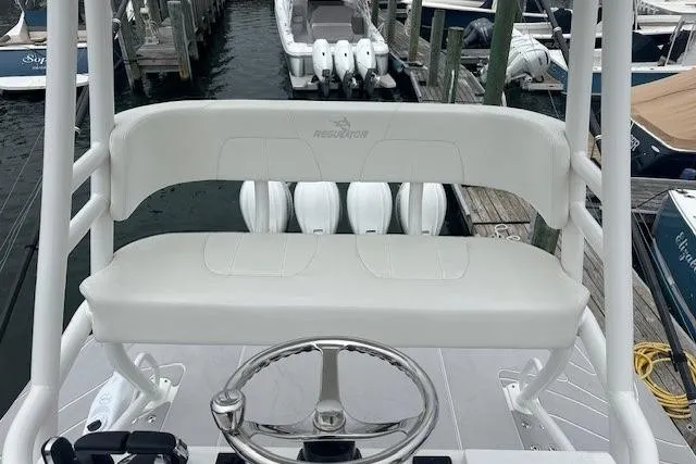 Slide: The Image of 2022 Regulator 41 boat helm with white seating and steering wheel at marina. - 33