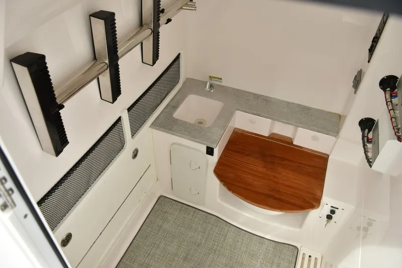 Slide: The Image of 2022 Everglades 335 Center Console interior with sink, wooden seat, and storage compartments. - 27