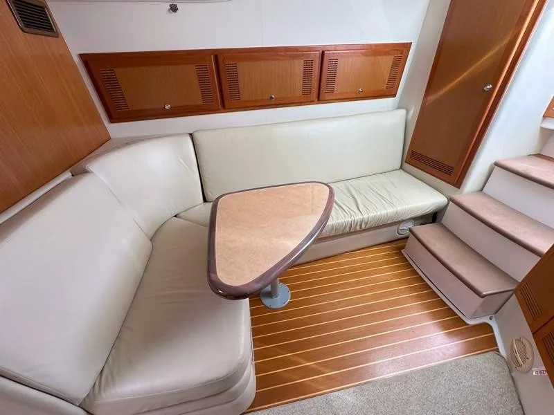 Slide: The Image of 2004 Cabo Express yacht interior with beige seating, wooden cabinets, and stairs. - 34