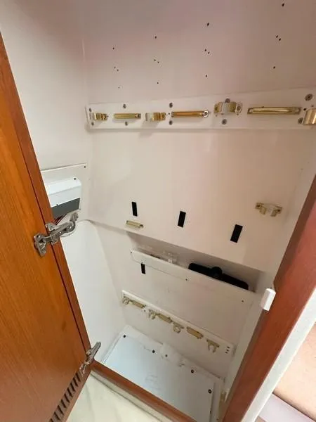 Slide: The Image of Empty storage cabinet inside 2004 Cabo Express boat, featuring wooden door and white interior. - 39