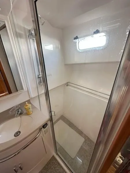 Slide: The Image of 2004 Cabo Express boat bathroom with shower, sink, and window. - 49
