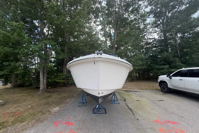 Slide: The Image of 2012 Everglades 230 Dual Console boat on stands, parked near a white vehicle. - 8