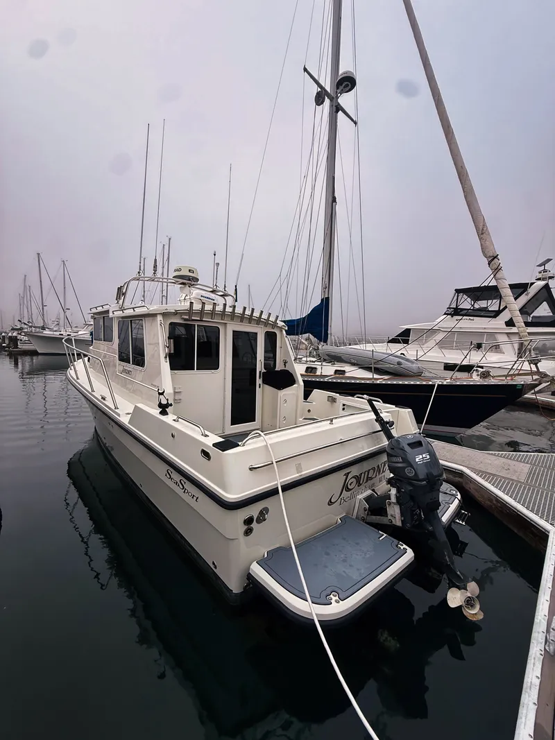 Slide: The Image of A 2005 SeaSport Voyager 3000 docked. It features a sturdy design and an outboard motor. - 27