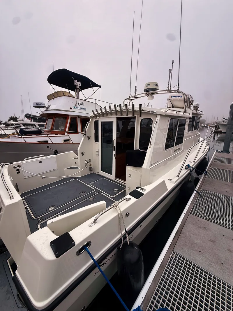 Slide: The Image of The 2005 SeaSport Voyager 3000 is docked, featuring a spacious aft deck and a white cabin. - 20