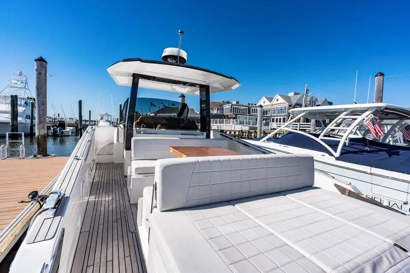 Slide: The Image of The image shows a 2023 Astondoa 377 Coupe Outboard at a dock. It features modern design with white upholstery and an outdoor wooden table. - 37