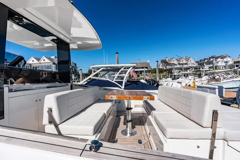 Slide: The Image of The image shows the cockpit of a 2023 Astondoa 377 Coupe Outboard with white seating and a wooden table. - 34