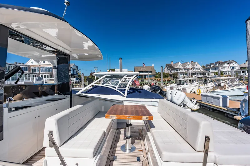 Slide: The Image of The image shows the deck of a 2023 Astondoa 377 Coupe Outboard with white seating and a wooden table. - 31