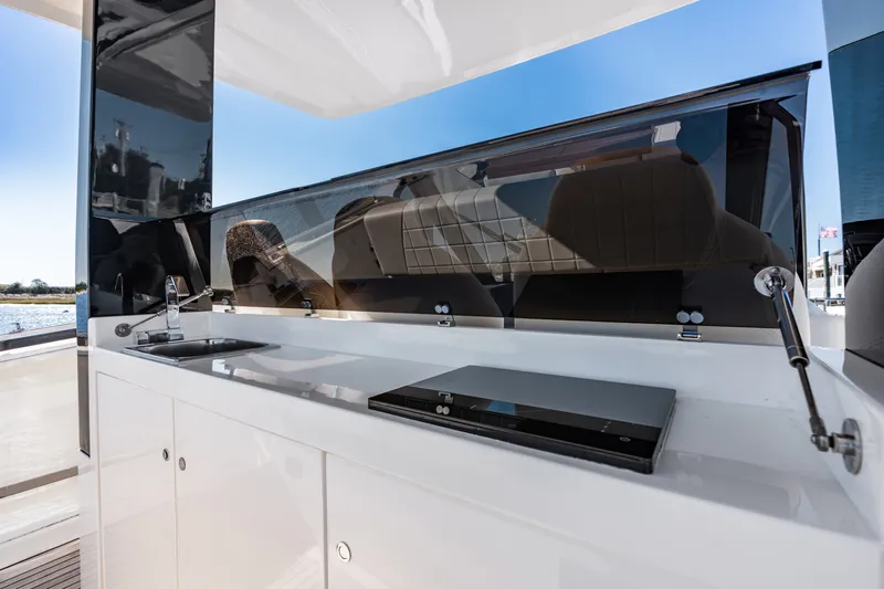 Slide: The Image of The 2023 Astondoa 377 Coupe Outboard features a sleek outdoor kitchen with a sink and cooktop. - 39