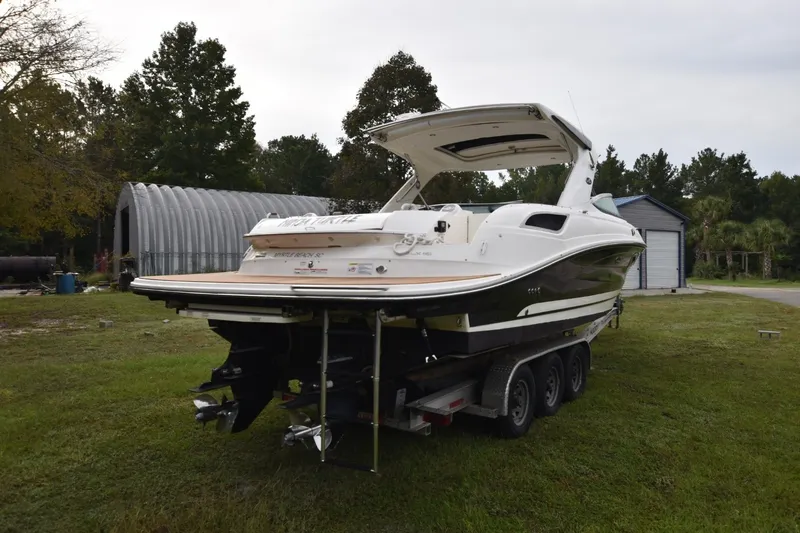 Slide: The Image of 2018 Sea Ray SLX 350 boat on trailer, parked on grassy area near trees and buildings. - 2