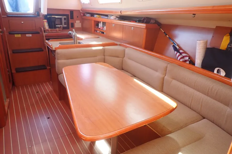 Slide: The Image of Interior of a 2008 Hunter 33 sailboat with wooden dining area and beige seating. - 17