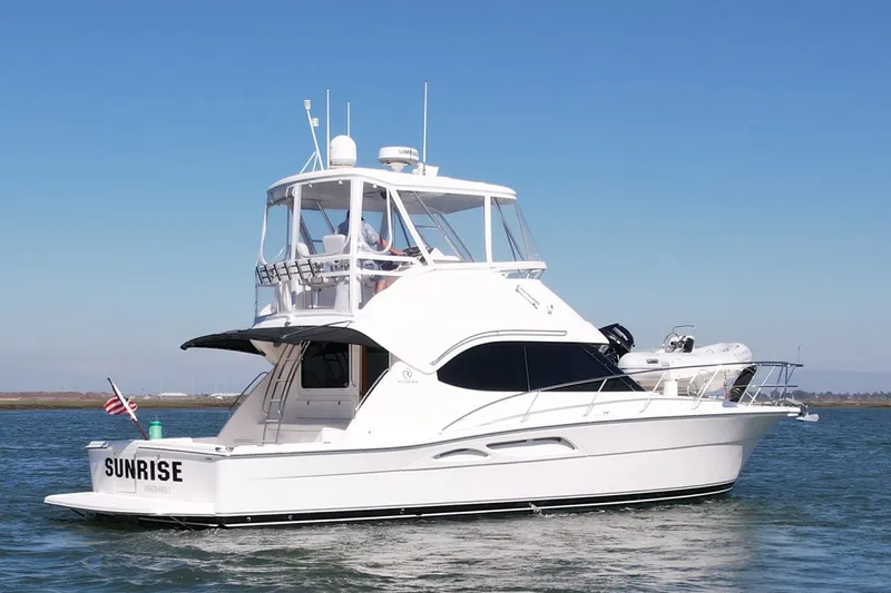 Slide: The Image of 2006 Riviera 40 Flybridge yacht cruising on calm waters under clear blue skies. - 2