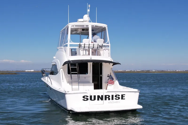 Slide: The Image of 2006 Riviera 40 Flybridge yacht named "Sunrise" on open water, rear view. - 10
