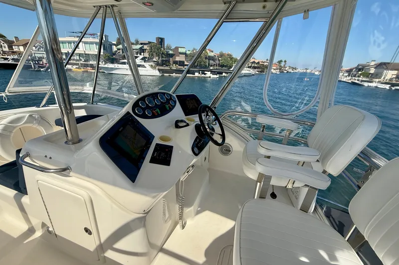 Slide: The Image of 2006 Riviera 40 Flybridge helm with modern controls, overlooking a scenic waterfront. - 78
