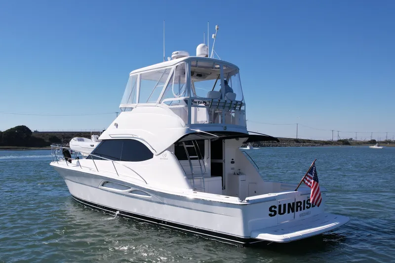 Slide: The Image of 2006 Riviera 40 Flybridge yacht on water, displaying American flag, clear sky background. - 4
