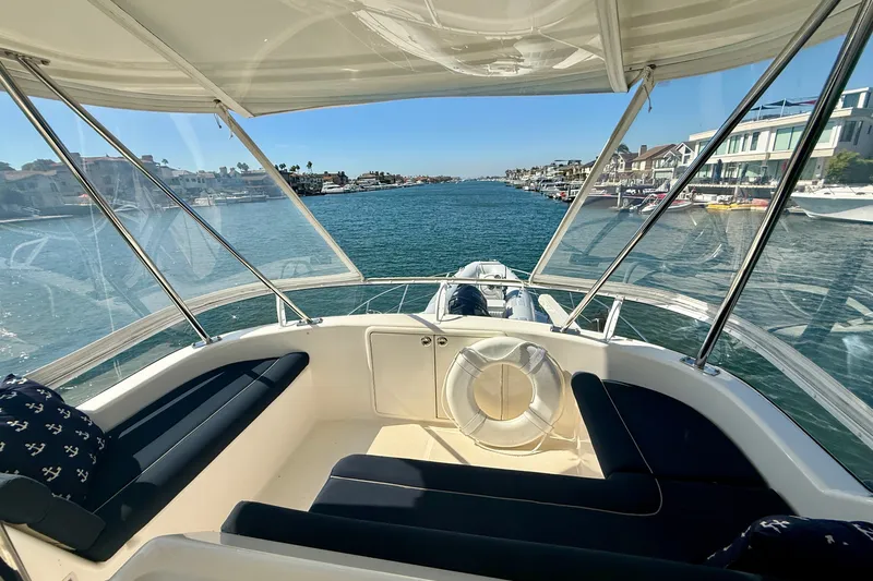 Slide: The Image of 2006 Riviera 40 Flybridge yacht interior with waterfront view, featuring comfortable seating and clear skies. - 85