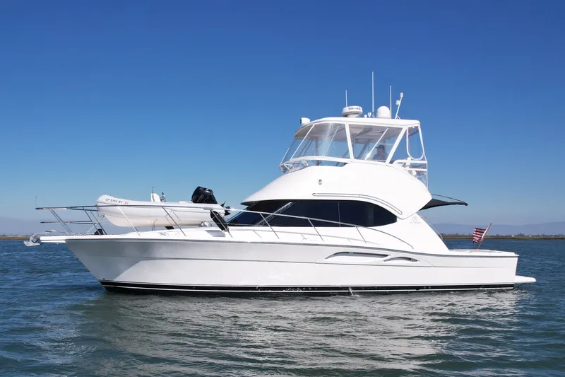 The Image of 2006 Riviera 40 Flybridge yacht cruising on calm waters under clear blue sky. - 0
