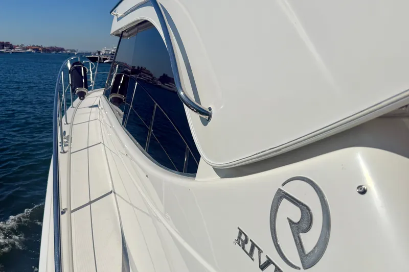 Slide: The Image of 2006 Riviera 40 Flybridge yacht cruising on a sunny day, showcasing sleek design and logo. - 91