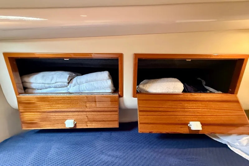 Slide: The Image of Wooden storage compartments with towels inside a 2006 Riviera 40 Flybridge yacht. - 56