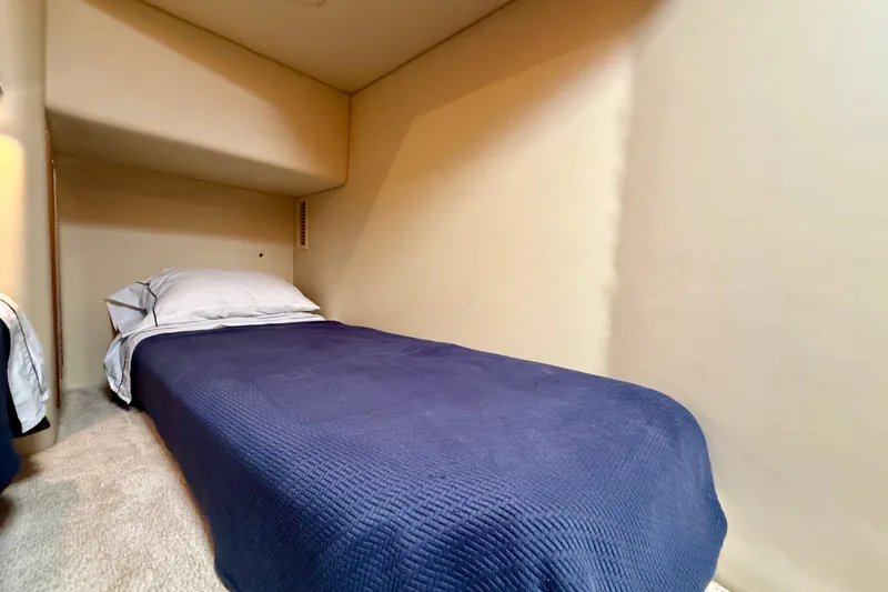 Slide: The Image of Single bed in 2006 Riviera 40 Flybridge cabin with blue bedding and beige walls. - 53