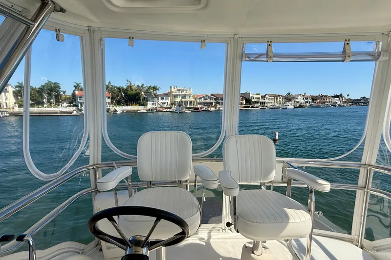Slide: The Image of Flybridge view from 2006 Riviera 40, overlooking serene waterfront homes and clear blue water. - 77
