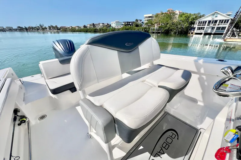 Slide: The Image of 2021 Robalo R242 Explorer boat interior with seating, steering wheel, and scenic waterfront view. - 18