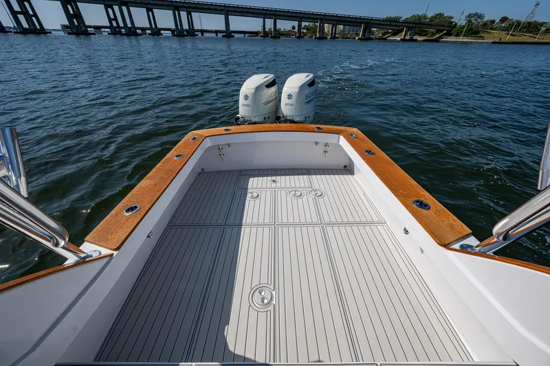 Slide: The Image of 2019 Custom Carolina Custom Express boat with twin engines on open water near a bridge. - 26