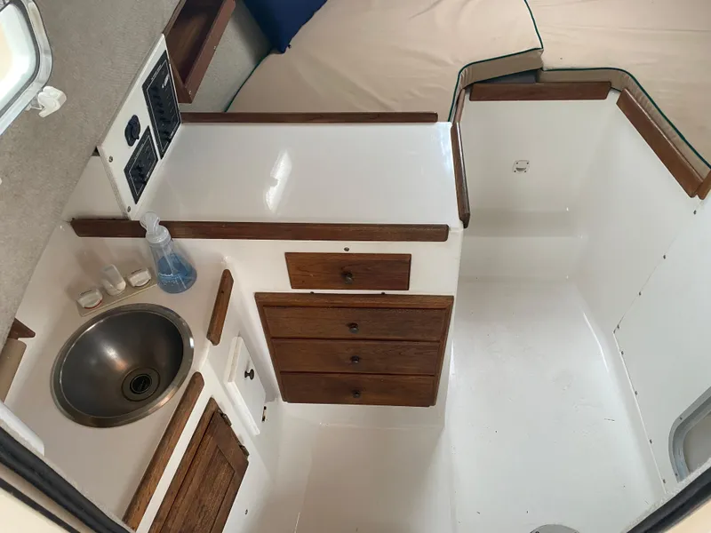Slide: The Image of 1999 Atlas Boat Works Acadia 25 interior with sink, wooden cabinets, and white countertop. - 9