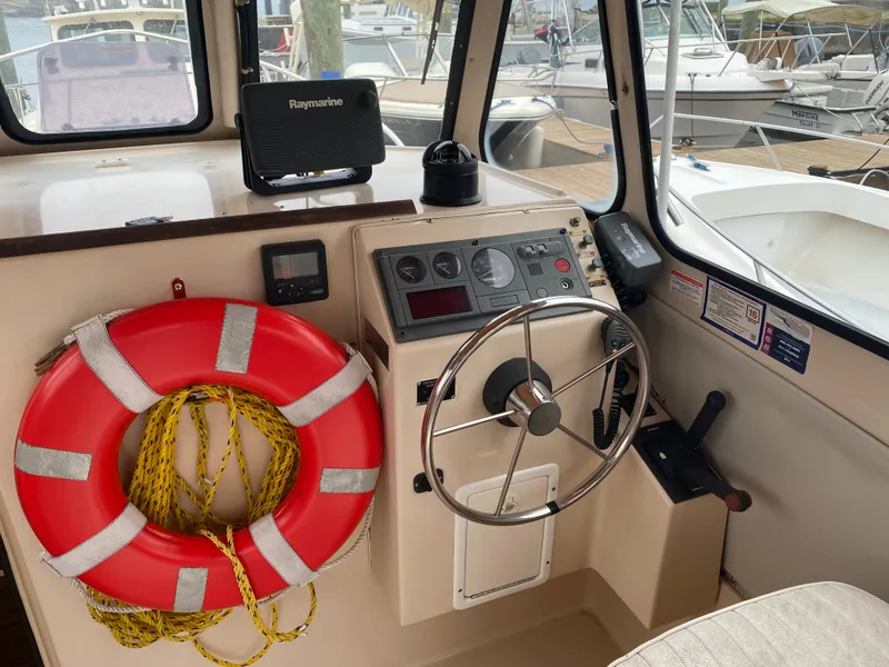 Slide: The Image of Interior helm of 1999 Atlas Boat Works Acadia 25 with steering wheel and life preserver. - 12