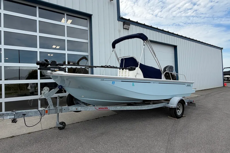 Slide: The Image of 2022 Boston Whaler 170 Montauk boat on trailer, parked outside a garage. - 1