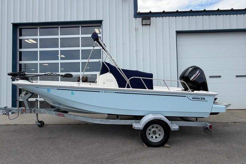Slide: The Image of 2022 Boston Whaler 170 Montauk boat on trailer, parked outside a garage. - 3