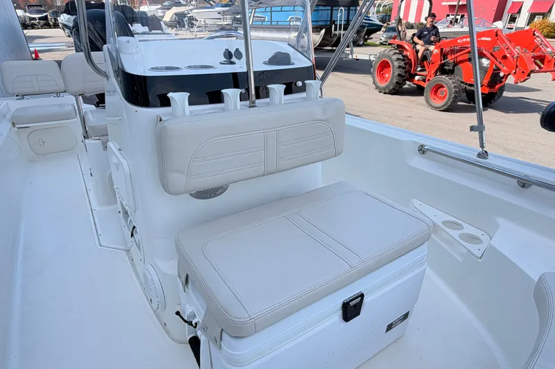 Slide: The Image of 2022 Boston Whaler 170 Montauk boat interior with seating and console, parked near a red tractor. - 9