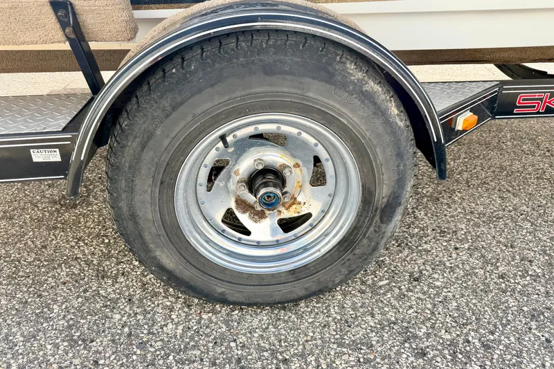 Slide: The Image of Trailer wheel of a 1994 Skeeter SS140 on asphalt surface. - 76