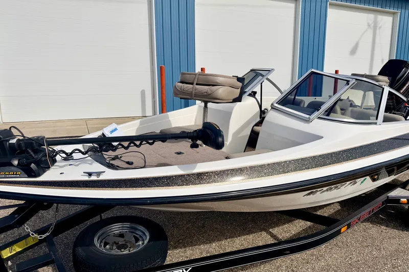 Slide: The Image of 1994 Skeeter SS140 boat with trolling motor, parked on a trailer near a blue building. - 20
