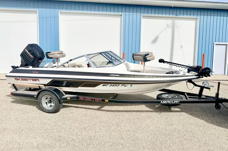Slide: The Image of 1994 Skeeter SS140 boat on trailer, parked outside blue building. - 3