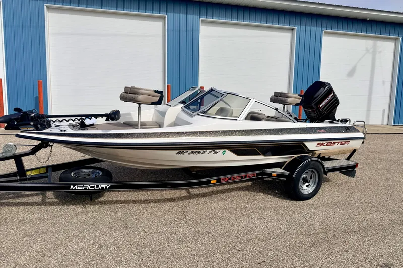 Slide: The Image of 1994 Skeeter SS140 boat on trailer, parked outside blue building. - 2