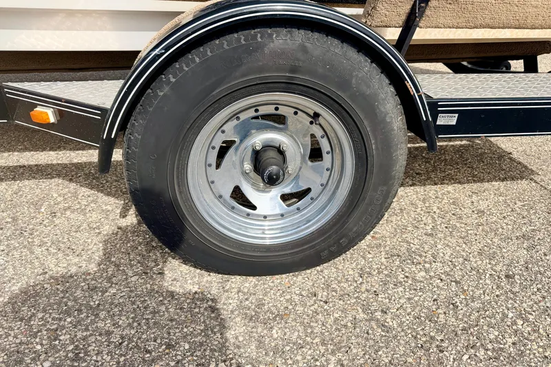 Slide: The Image of Trailer wheel of a 1994 Skeeter SS140 boat on asphalt surface. - 75