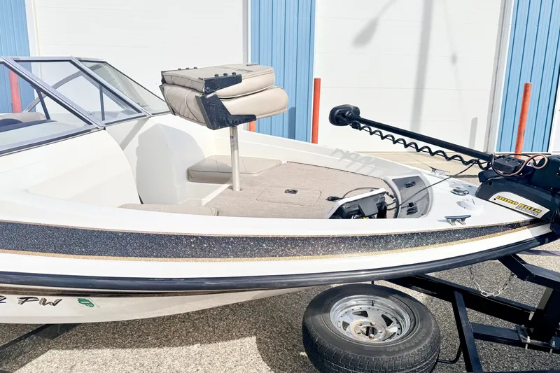 Slide: The Image of 1994 Skeeter SS140 boat with trolling motor, parked on trailer, near blue building. - 11