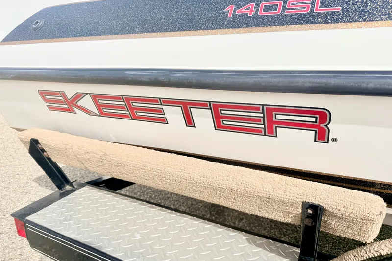 Slide: The Image of 1994 Skeeter SS140 boat with red logo on trailer, featuring diamond plate step. - 7