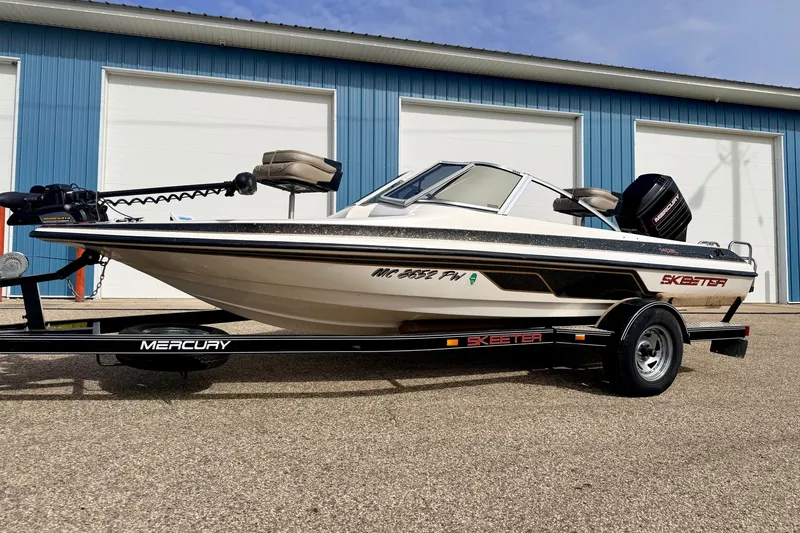 Slide: The Image of 1994 Skeeter SS140 boat on trailer, parked outside blue garage doors. - 6
