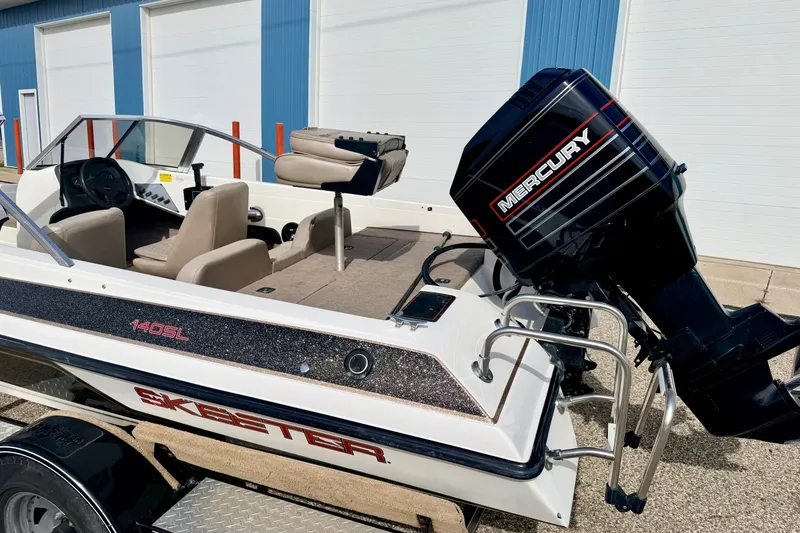 Slide: The Image of 1994 Skeeter SS140 boat with Mercury outboard motor, parked near blue building. - 19
