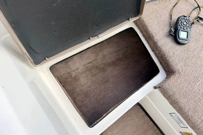 Slide: The Image of Open storage compartment in 1994 Skeeter SS140 boat with remote control nearby. - 55