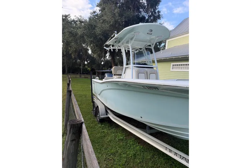 The Image of 2016 Sea Fox 246 Commander boat on trailer, parked beside a wooden fence and house. - 0