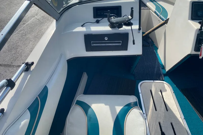 Slide: The Image of Interior of a 1994 Sunbird Corsair 170 boat, featuring white and teal seating. - 8