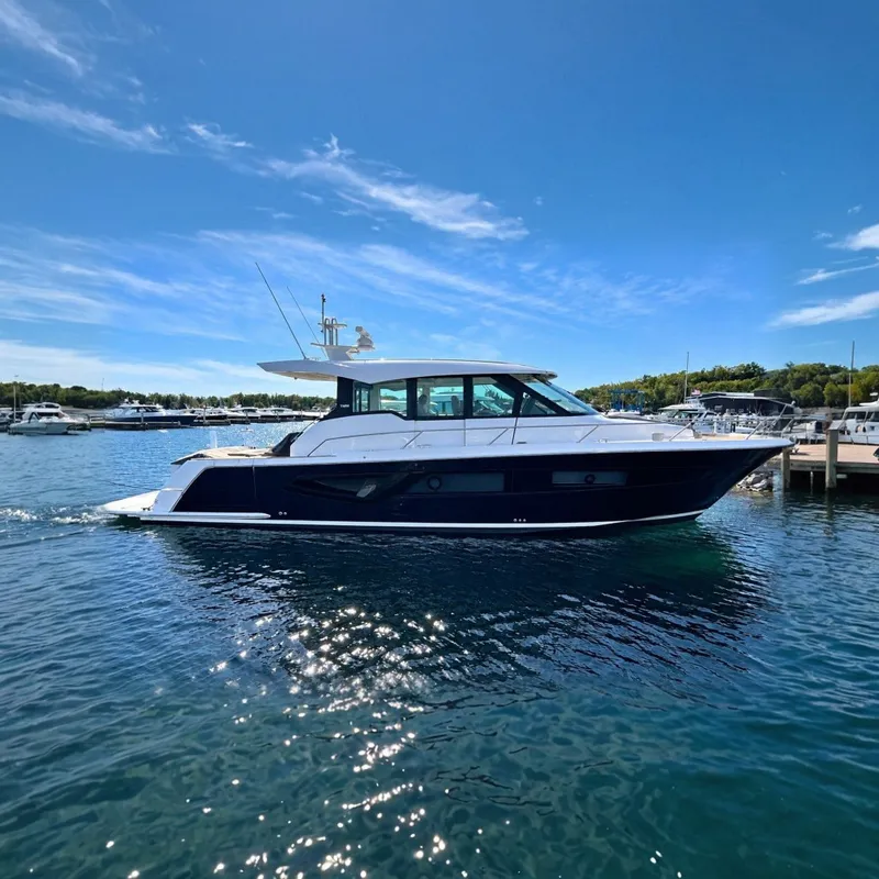The Image of The 2026 Tiara Yachts EX 54 glides elegantly on the water, surrounded by a sunny marina. - 0