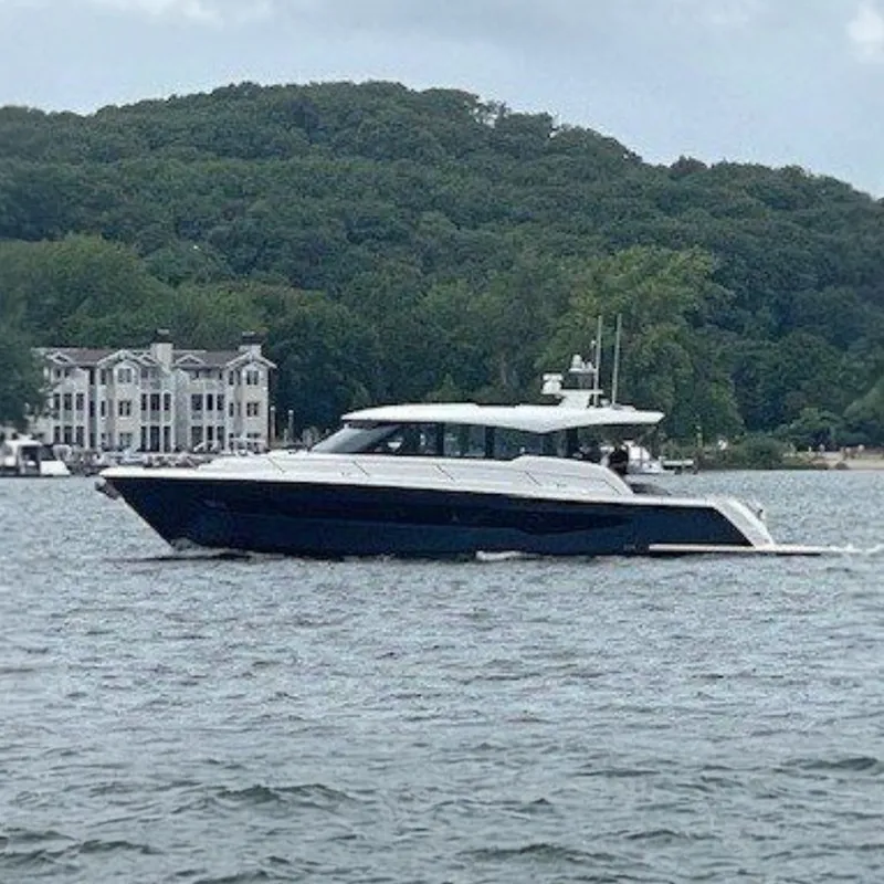 The Image of The 2026 Tiara Yachts EX 54 cruises on calm waters with a wooded shoreline in the background. - 0