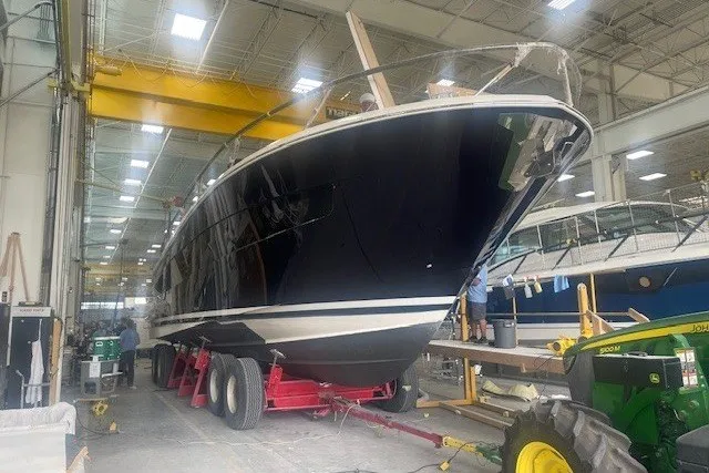 Slide: The Image of 2026 Tiara Yachts EX 54 in a shipyard, under construction with industrial equipment. - 4