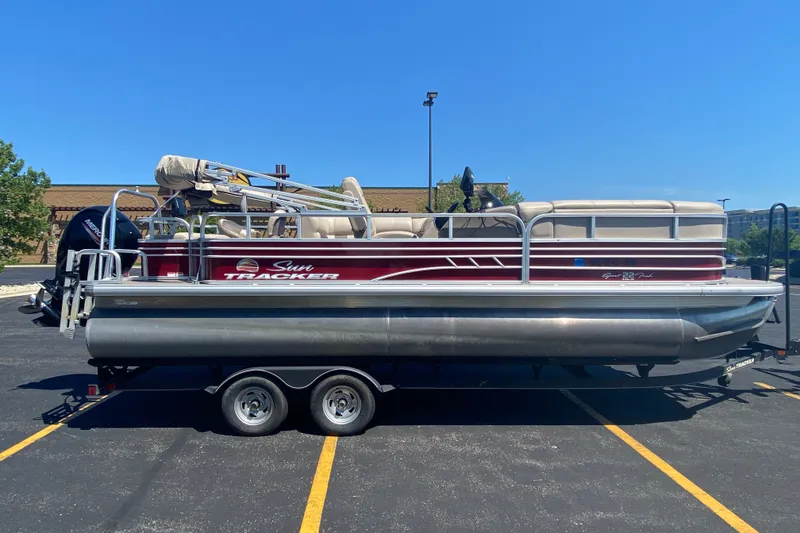 The Image of 2020 SUNTRACKER Sportfish 22 pontoon boat on trailer in parking lot. - 0