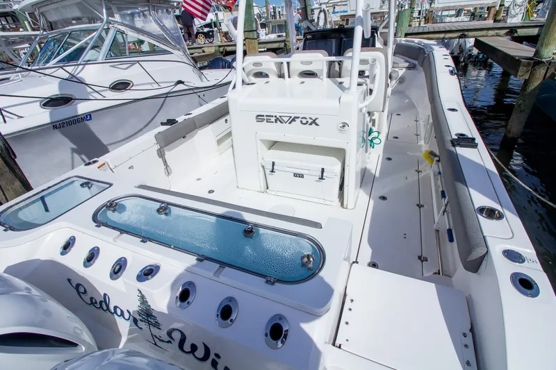 Slide: The Image of The image shows a 2019 Sea Fox 328 Commander boat. It features a spacious deck with rod holders and a large livewell. - 45