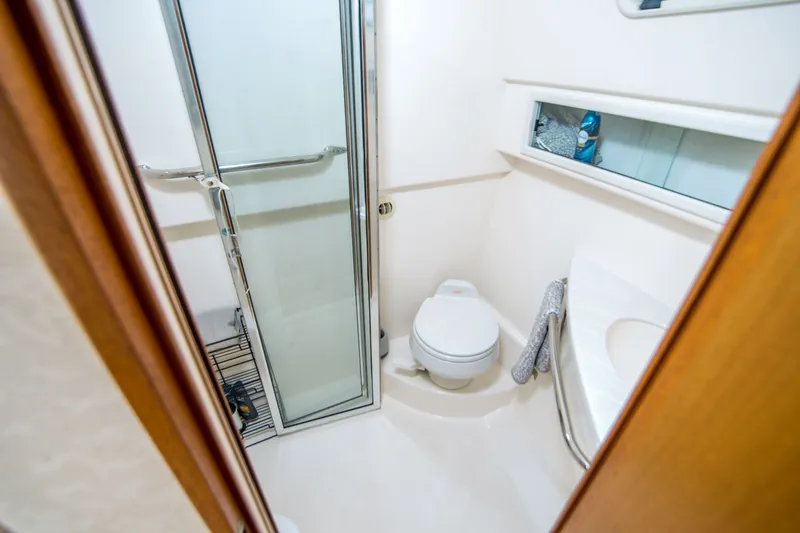 Slide: The Image of Compact bathroom in a 2005 Cabo 35 Express boat, featuring shower and toilet. - 21