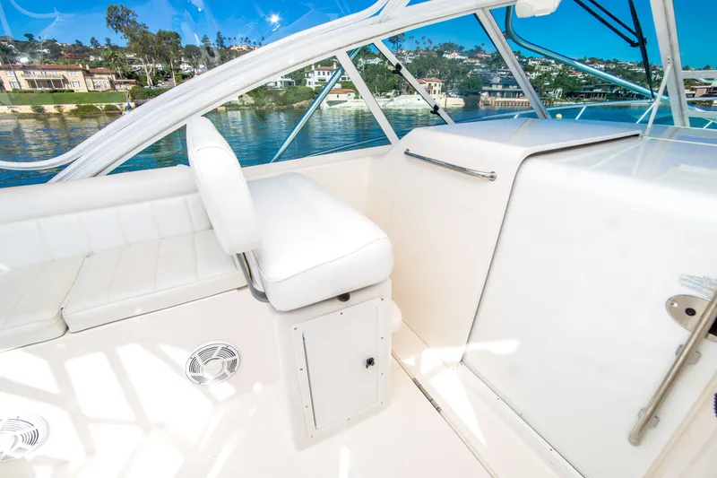 Slide: The Image of 2005 Cabo 35 Express boat interior with white seating and scenic waterfront view. - 13